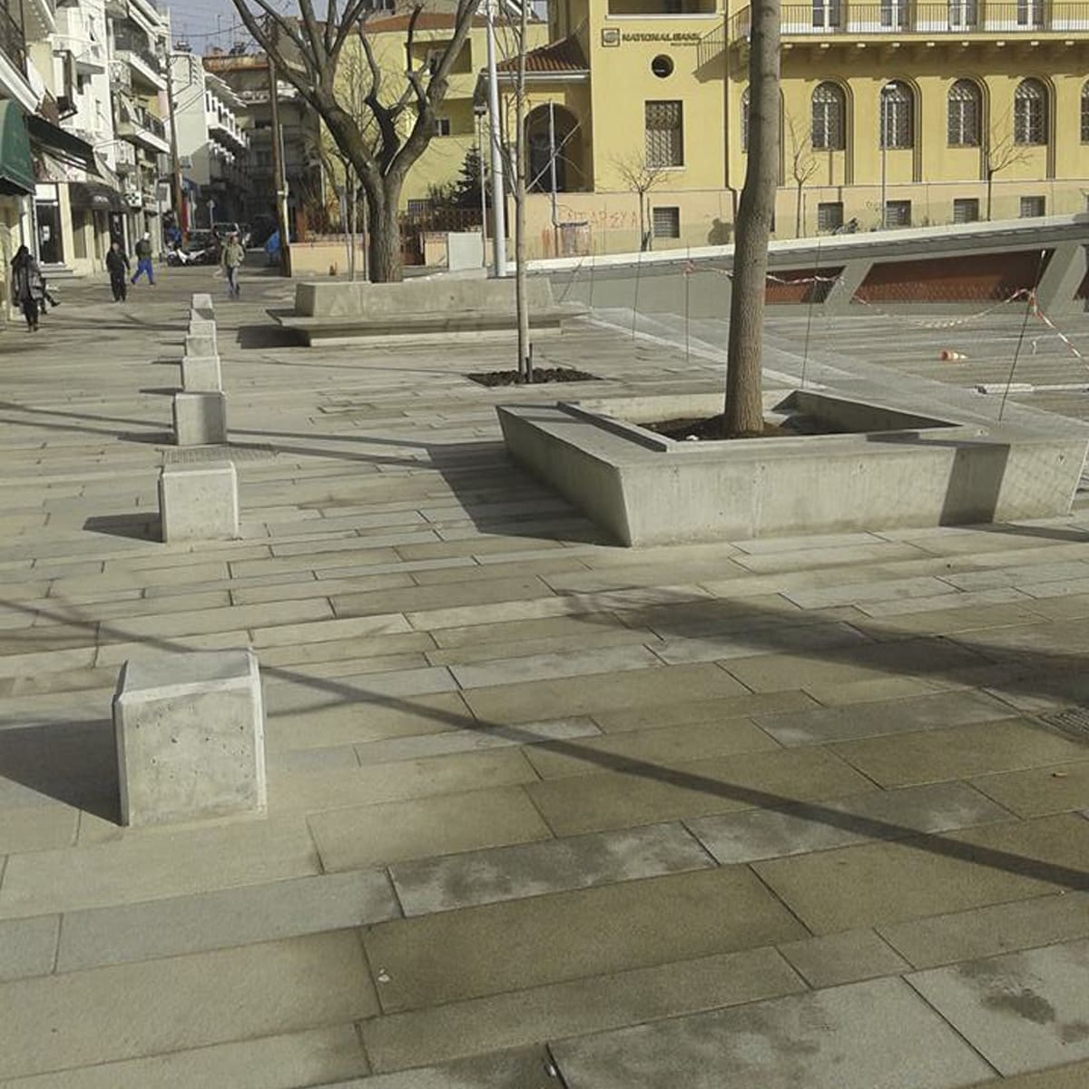Large-format stone paving and concrete planters in a public plaza