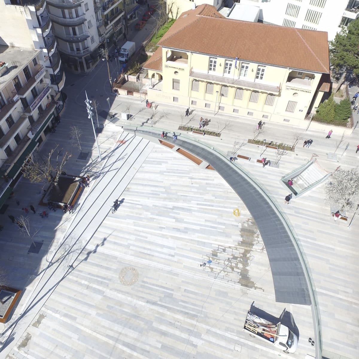 Aerial view of a marble-paved plaza and curved canopy
